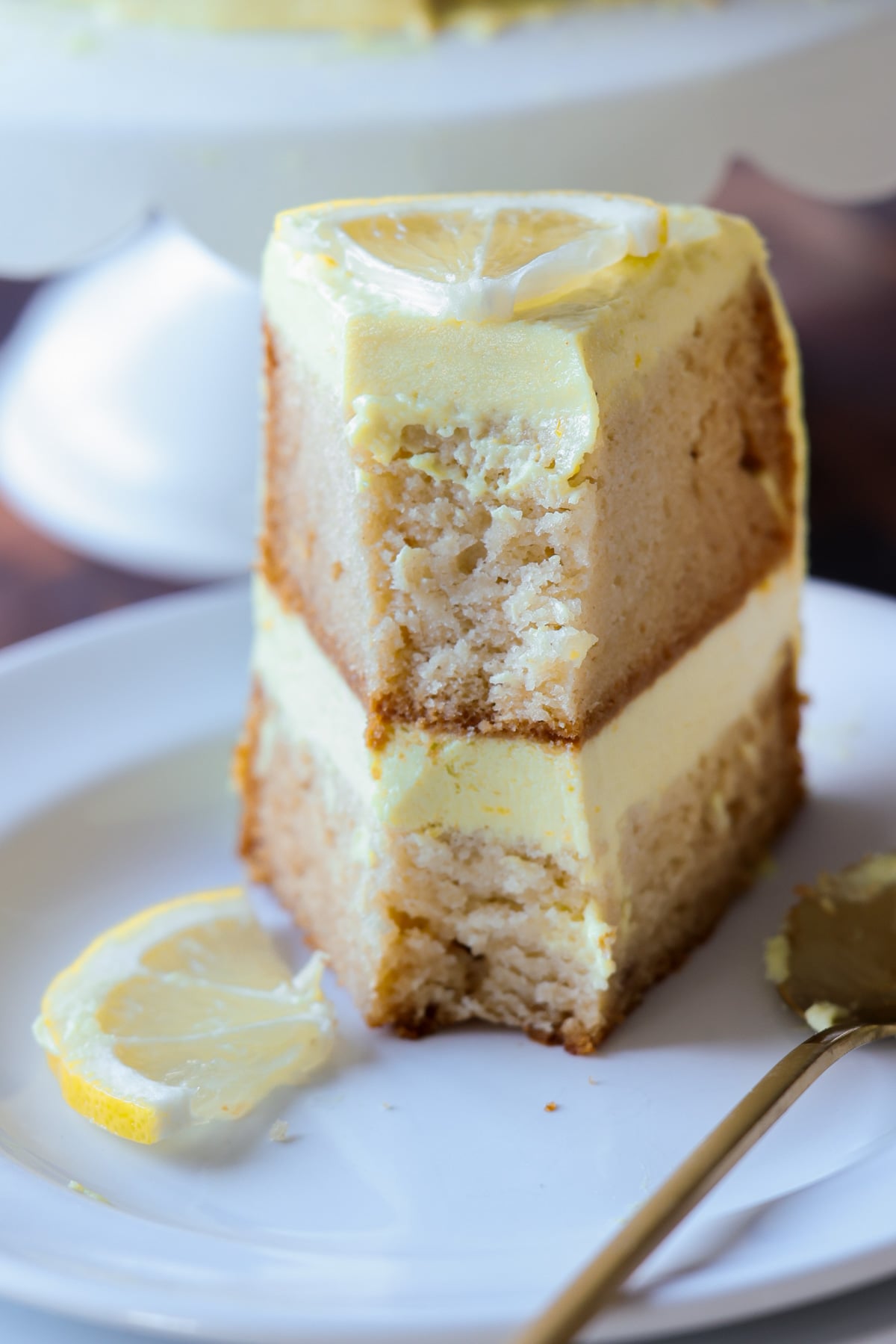 vegan lemon cake on the cake stand next to slices of the cake