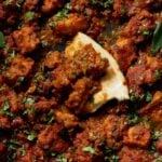 close-up of Madurai Chicken Curry in the pan with a piece of flatbread in it