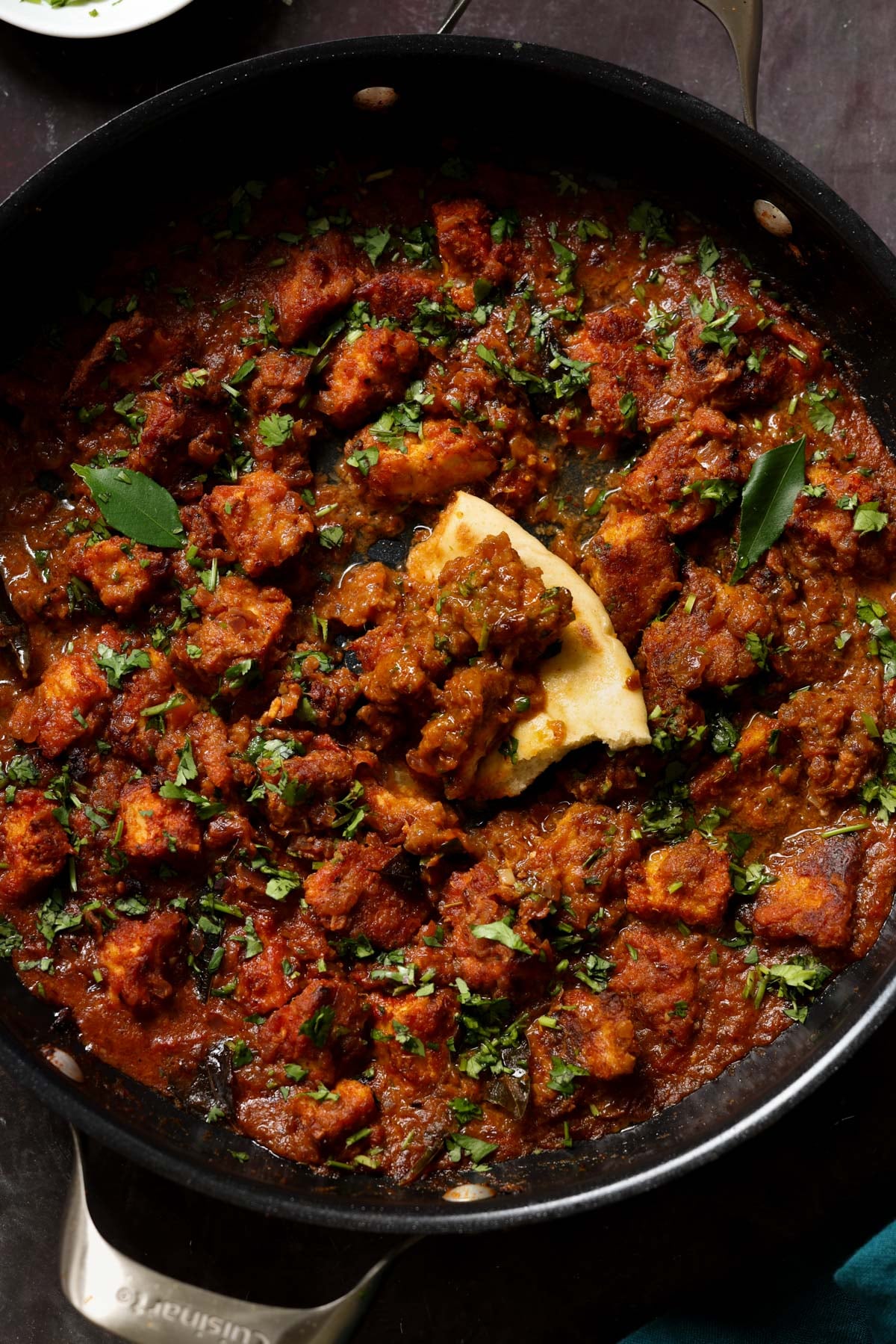 Madurai Chicken Curry in the pan with a piece of flatbread in it