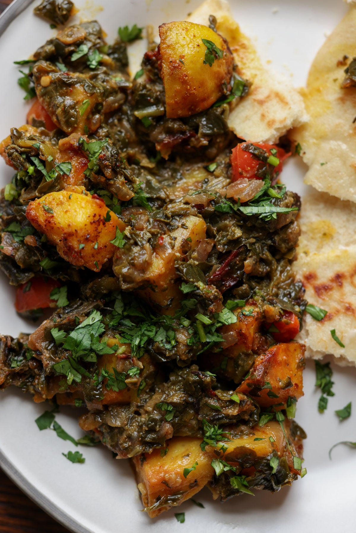 saag aloo on the plate with flatbread on the side