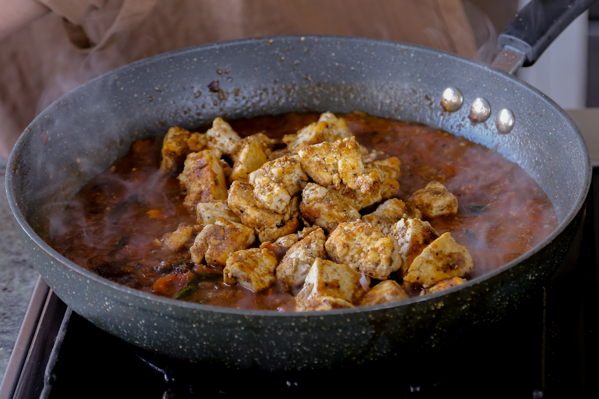 adding crisped up tofu to the Chettinad pepper chicken sauce in the pan