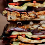 hands holding a sliced grilled veggie sandwich