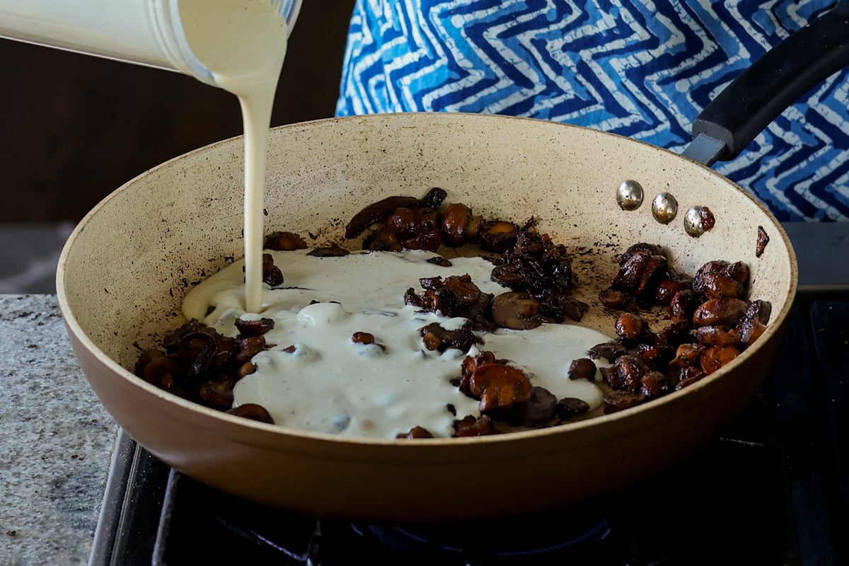 adding cream sauce to the mushrooms