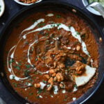 balchao mushrooms in the pan with a piece of flatbread dipped into it next to a bowl of crispy beans