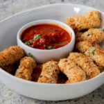 vegan mozzarella sticks in a serving platter with marinara on the side
