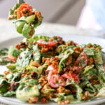 fork taking a bite of summer spinach salad with chickpea olive crumbles