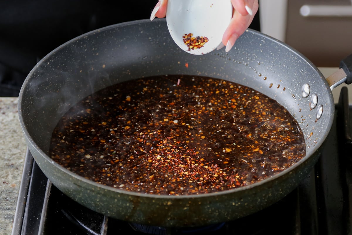 adding pepper flakes to the pan