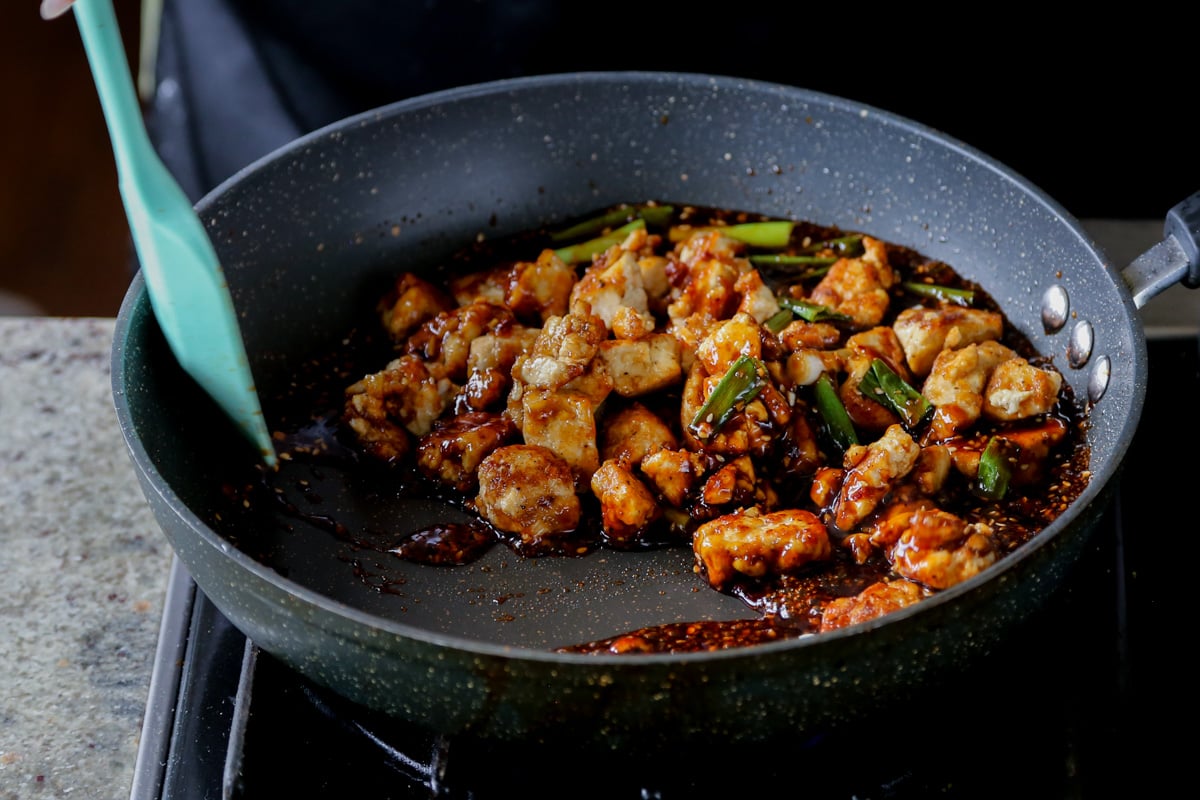 tossing tofu in the teriyaki sauce