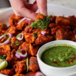 dipping a piece of tofu Koliwada into the mint chutney