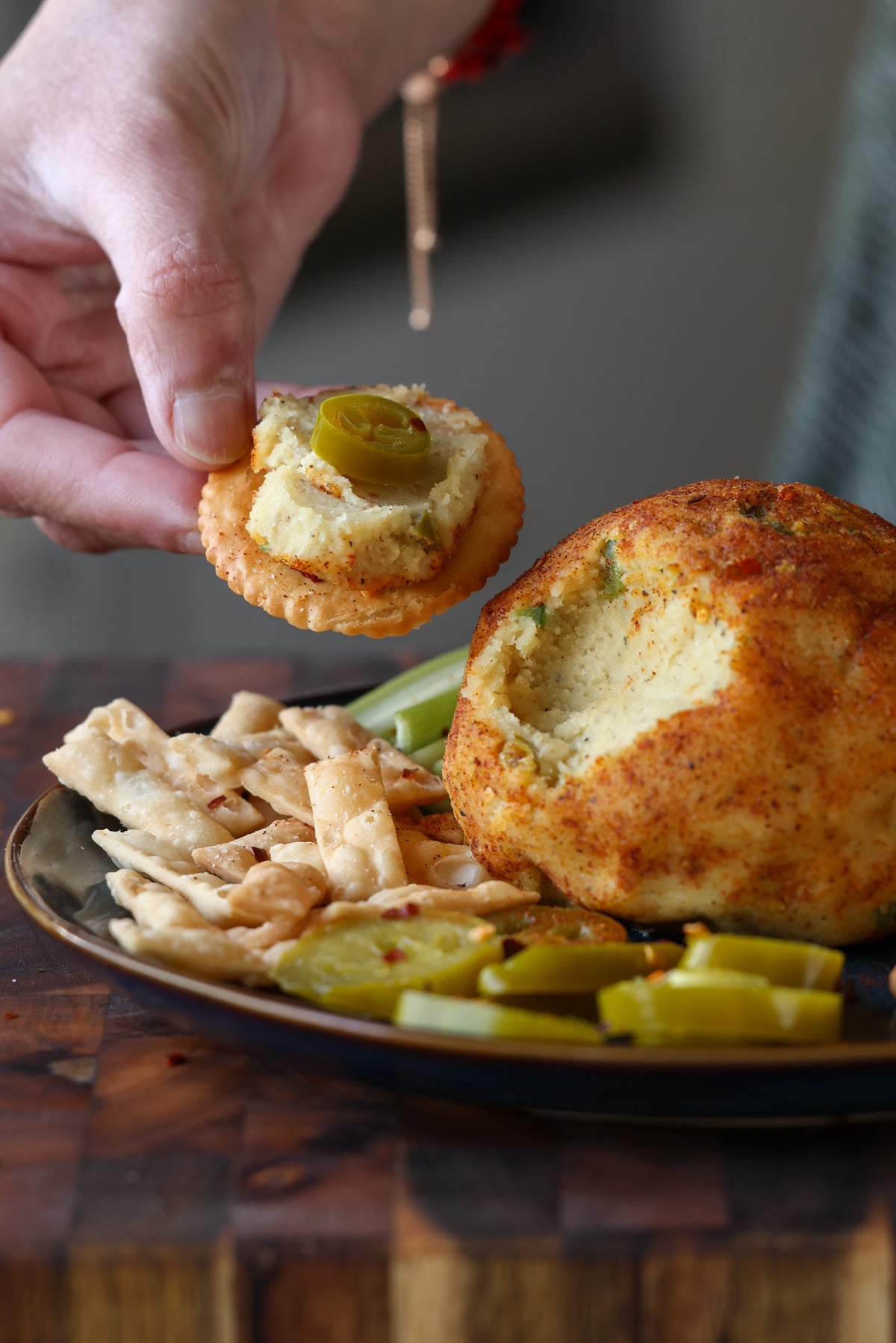 hand serving some jalapeño popper cheese ball onto a cracker