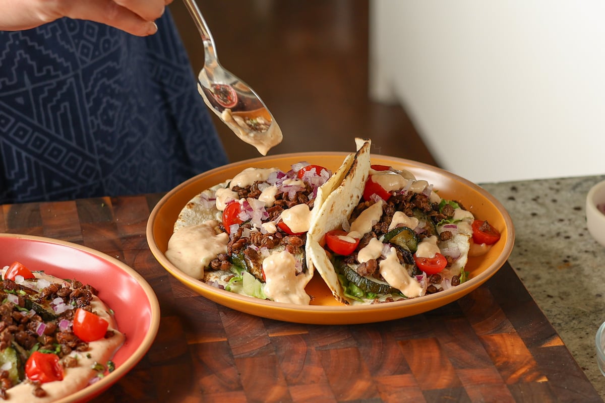 assembling the chipotle whipped tofu, roasted zucchini, and crispy lentils tacos