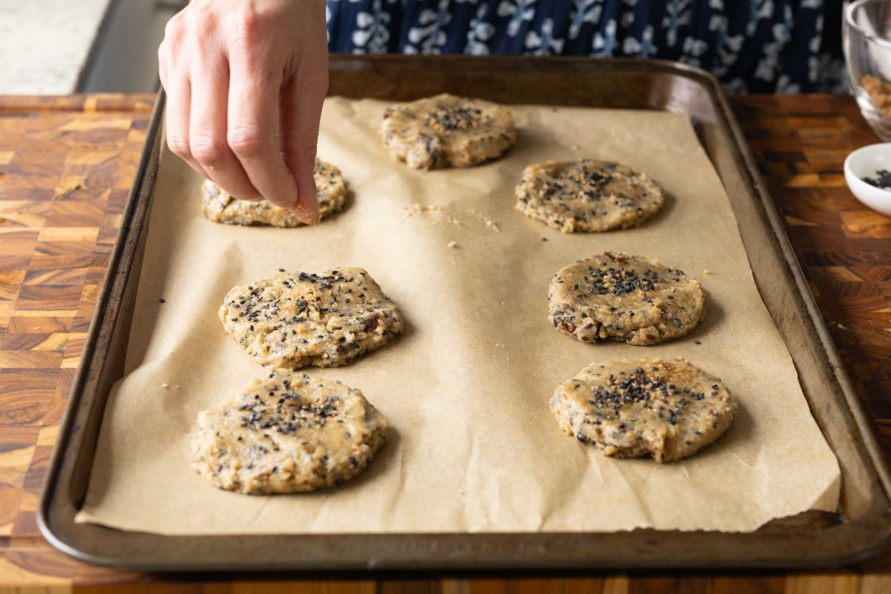 sprinkling black sesame seeds onto flattened cookies