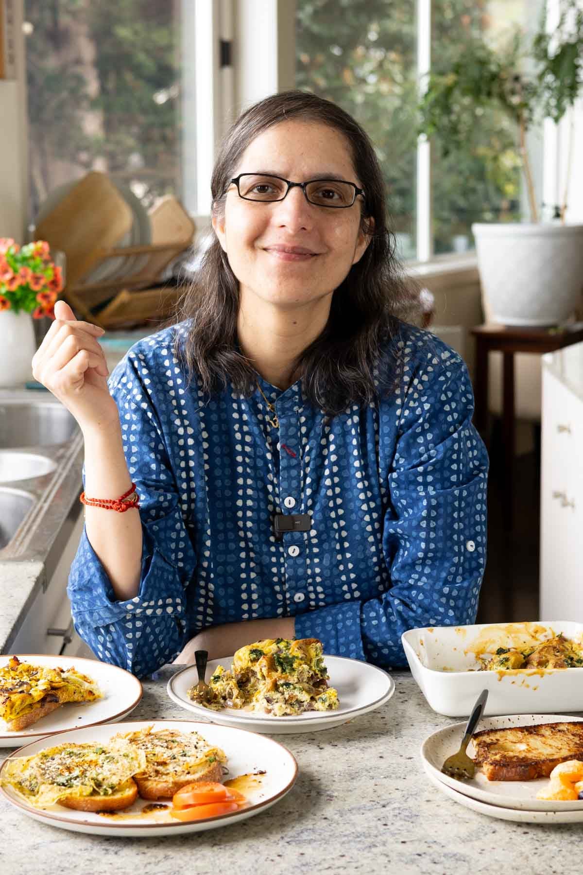 Vegan Richa at the kitchen counter in front of whipped tofu recipes on plates
