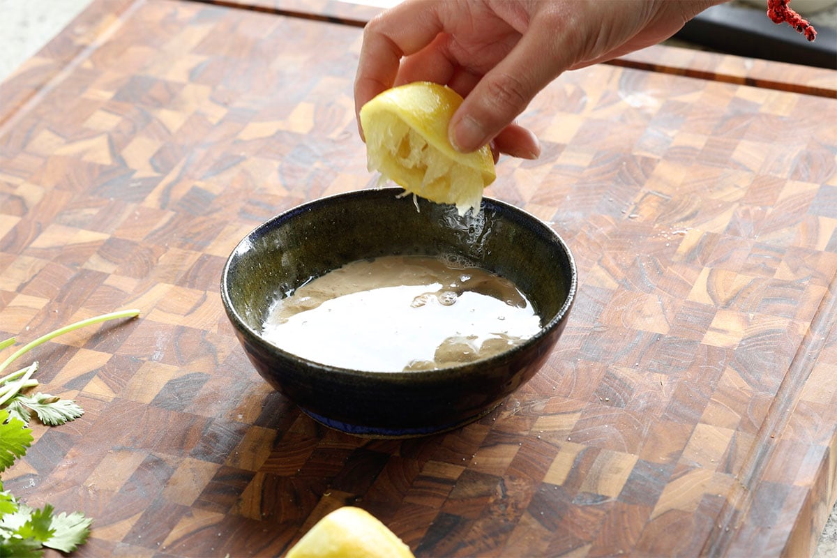 adding tahini sauce ingredients to the bowl