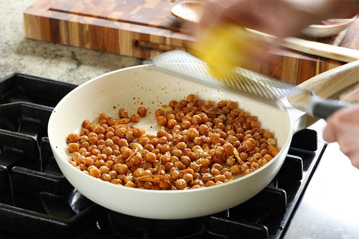 adding lemon zest to the chickpeas in the pan