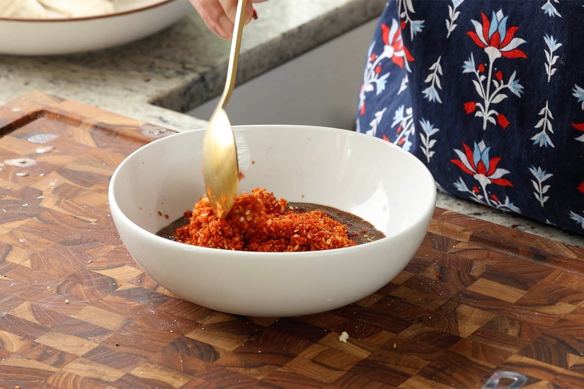adding chili garlic coconut chutney ingredients to the bowl