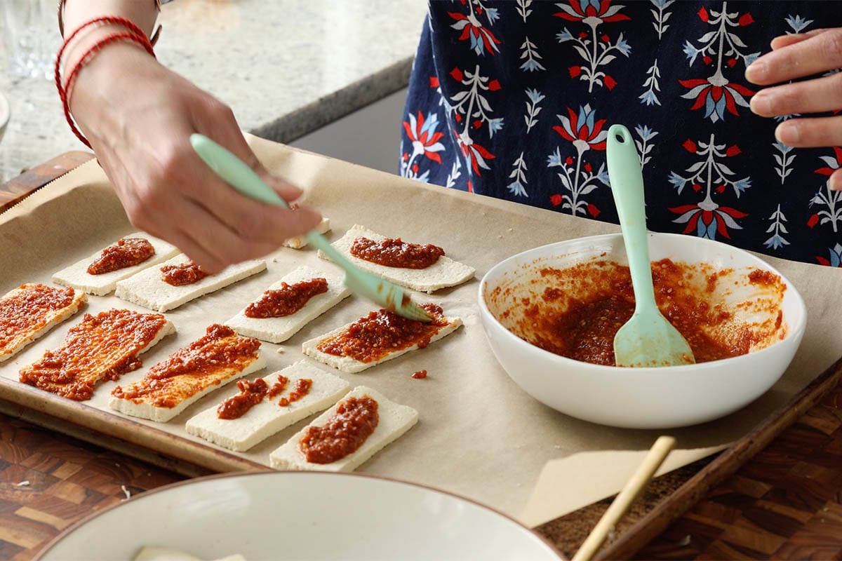 brushing the tofu with chili garlic coconut chutney before the first bake
