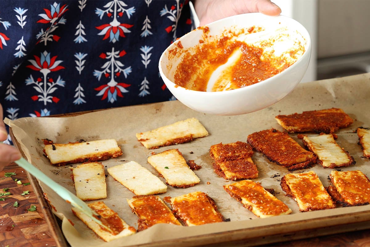brushing the tofu with chili garlic coconut chutney after the first bake