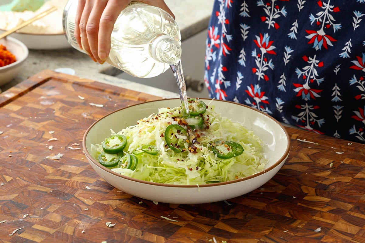 adding pickled cabbage ingredients to the bowl