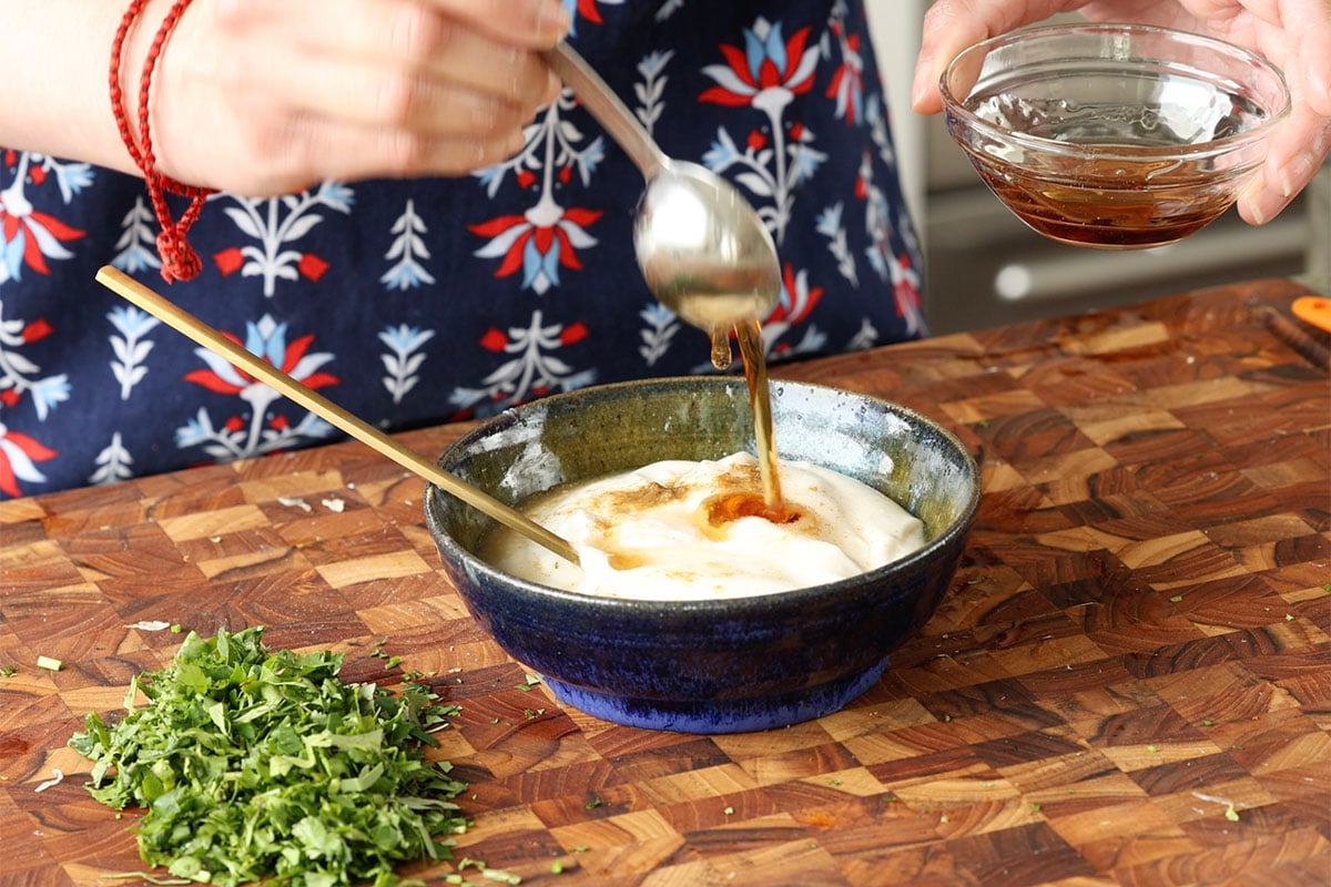 adding yogurt sauce ingredients to the bowl