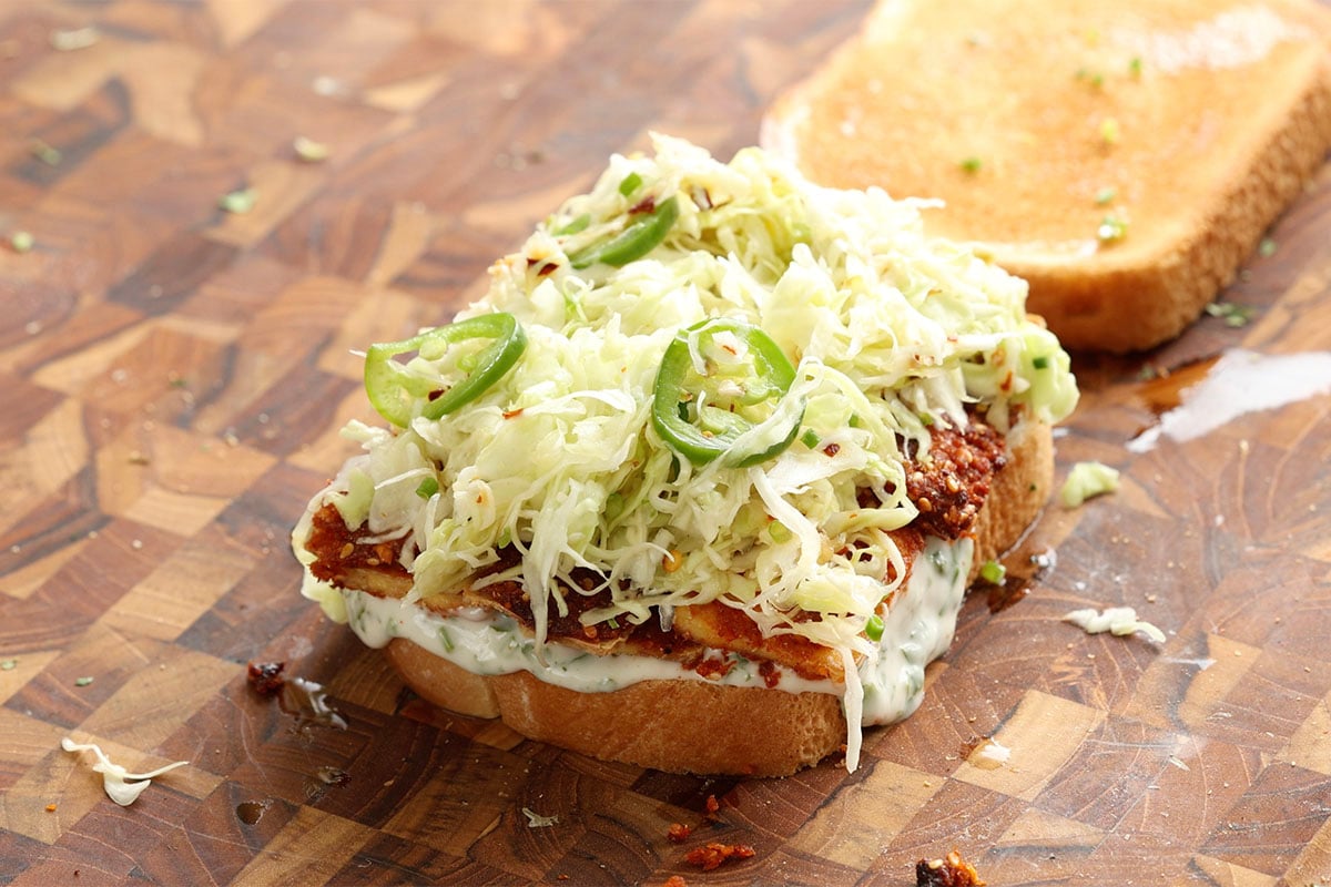 adding the pickled cabbage to the sandwich