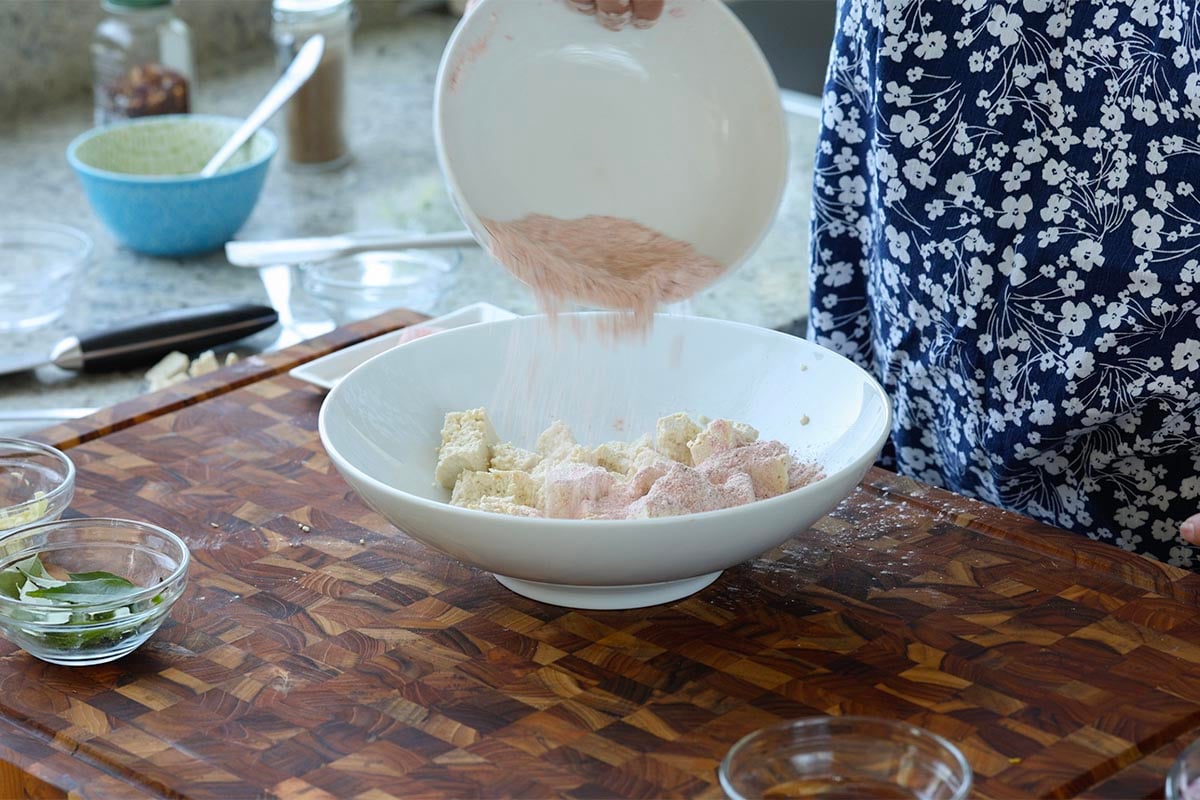 pouring the spice mixture onto the torn tofu