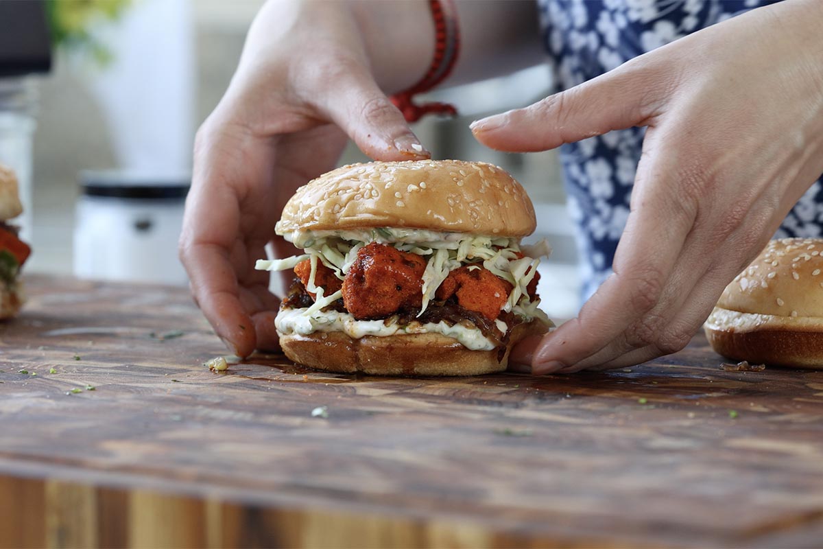 hands picking up the curry tofu sandwich