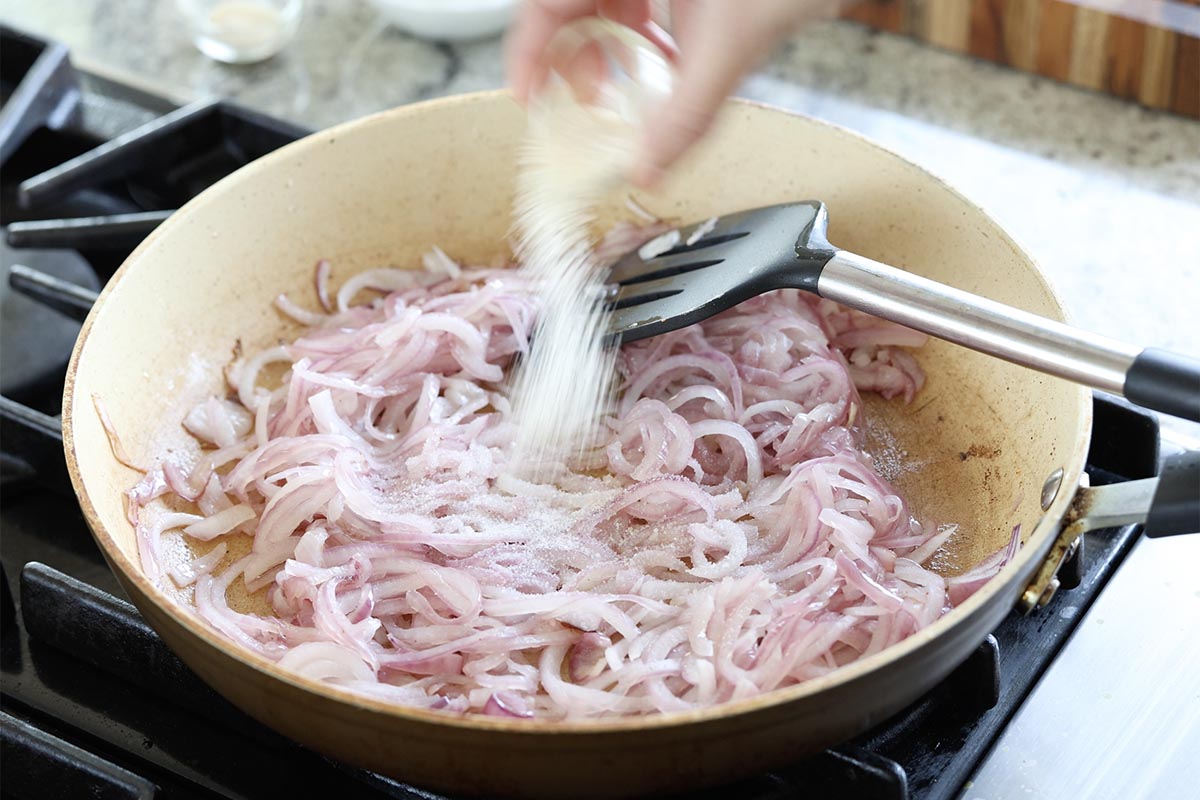 adding sugar and salt to the onions