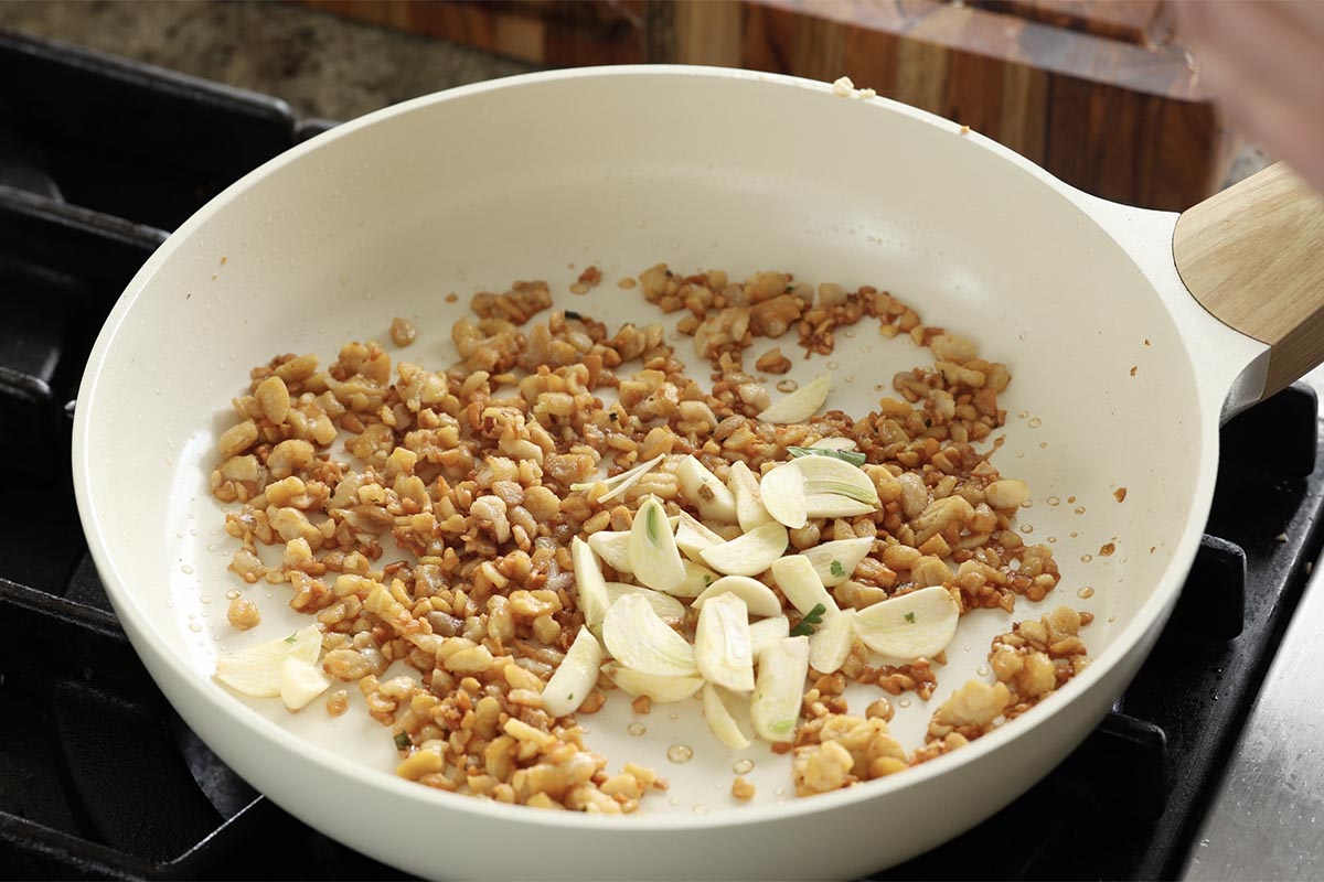adding sliced garlic to the crumbled tempeh