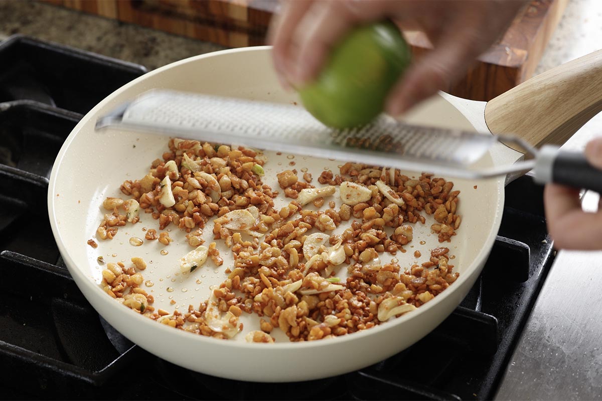grating lime zest over the cooked tempeh and garlic