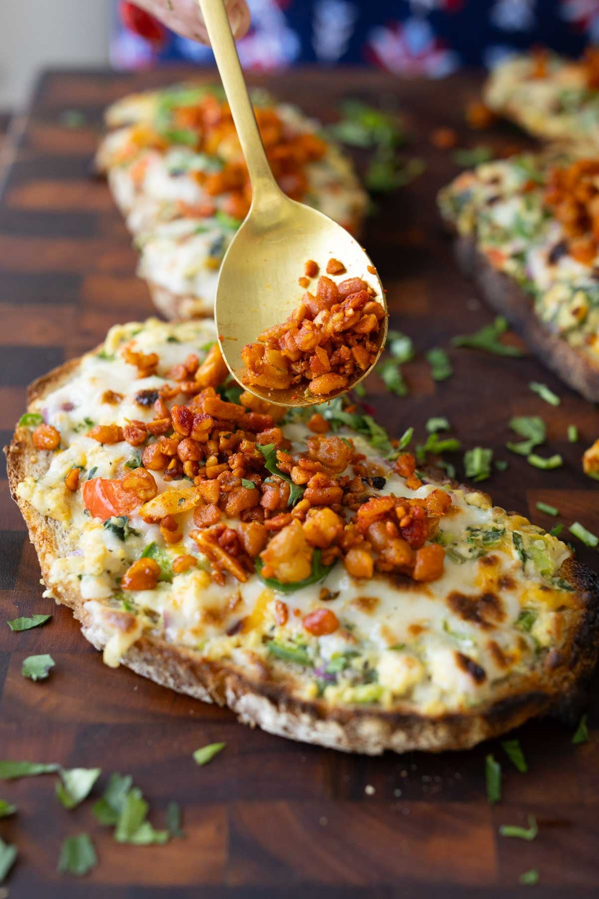 sprinkling the crispy tempeh topping onto the Indian chilli cheese toasts