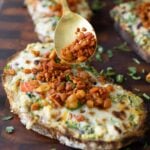 sprinkling the crispy tempeh topping onto the Indian chilli cheese toasts