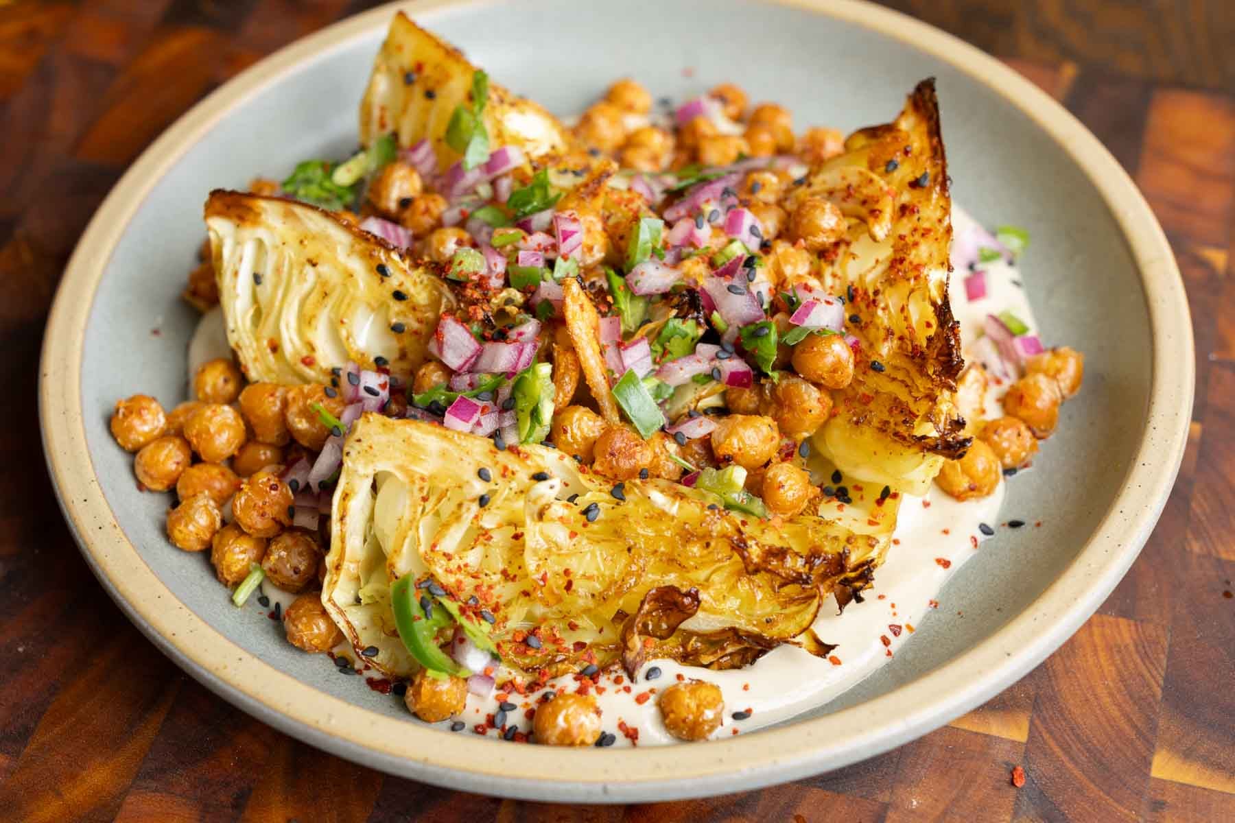 roasted cabbage wedges on a bed of tahini sauce with crispy chickpeas and gremolata