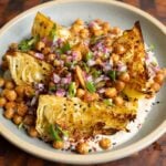 roasted cabbage wedges on a bed of tahini sauce with crispy chickpeas and gremolata