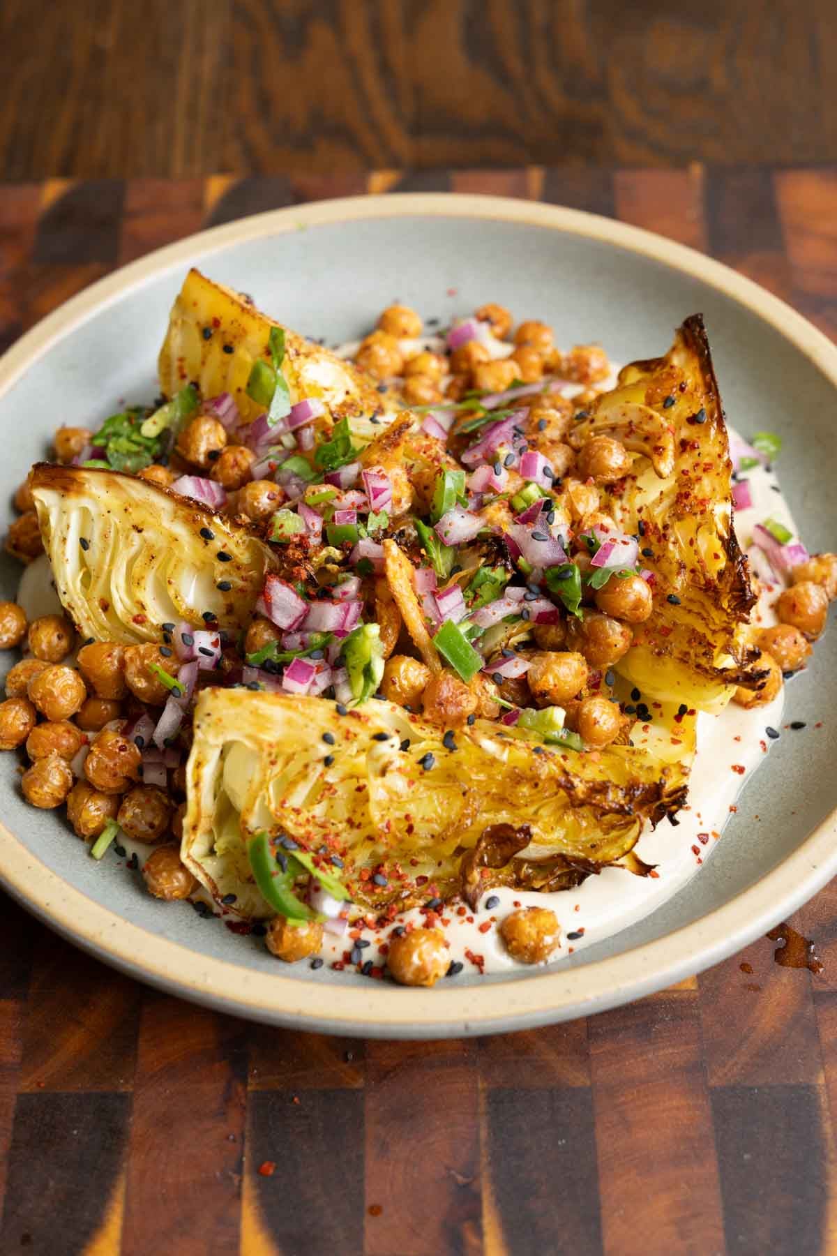 roasted cabbage wedges on a bed of tahini sauce with crispy chickpeas and gremolata