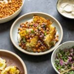 roasted cabbage wedges on a bed of tahini sauce with crispy chickpeas and gremolata surrounded by bowls of each component