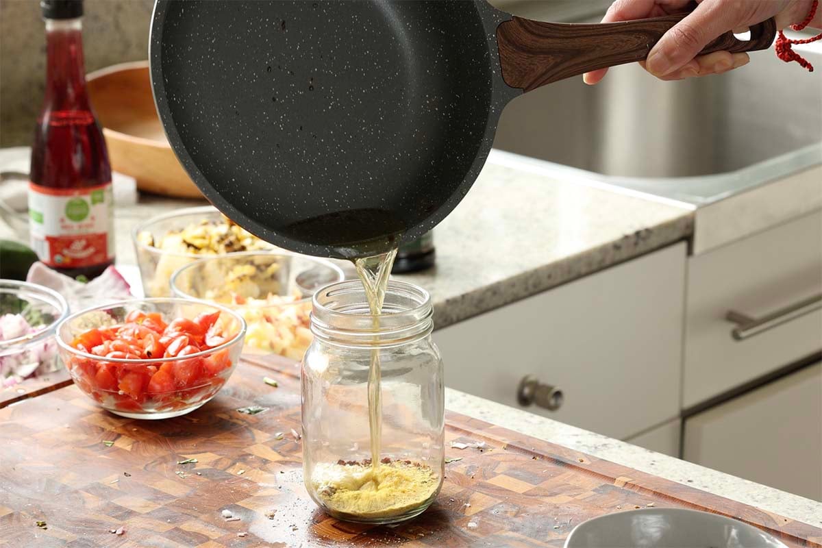 pouring the hot caper oil into the jar of spices