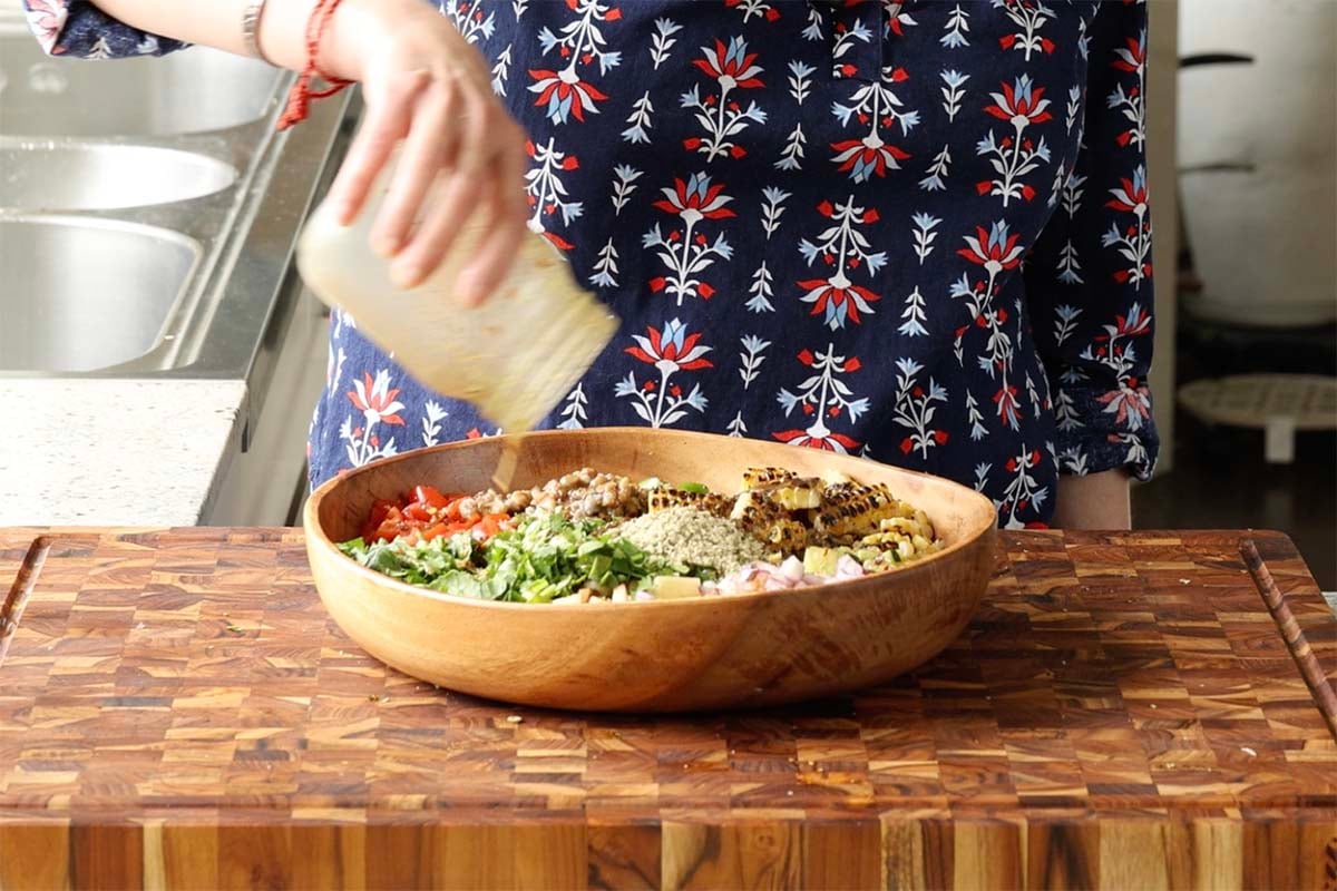 adding dressing to the bowl of lentil salad ingredients