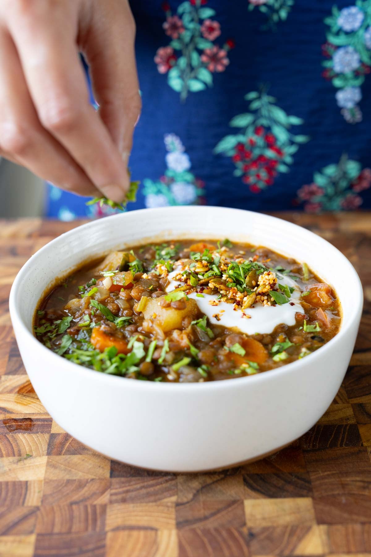 sprinkling cilantro onto the lentil potato soup