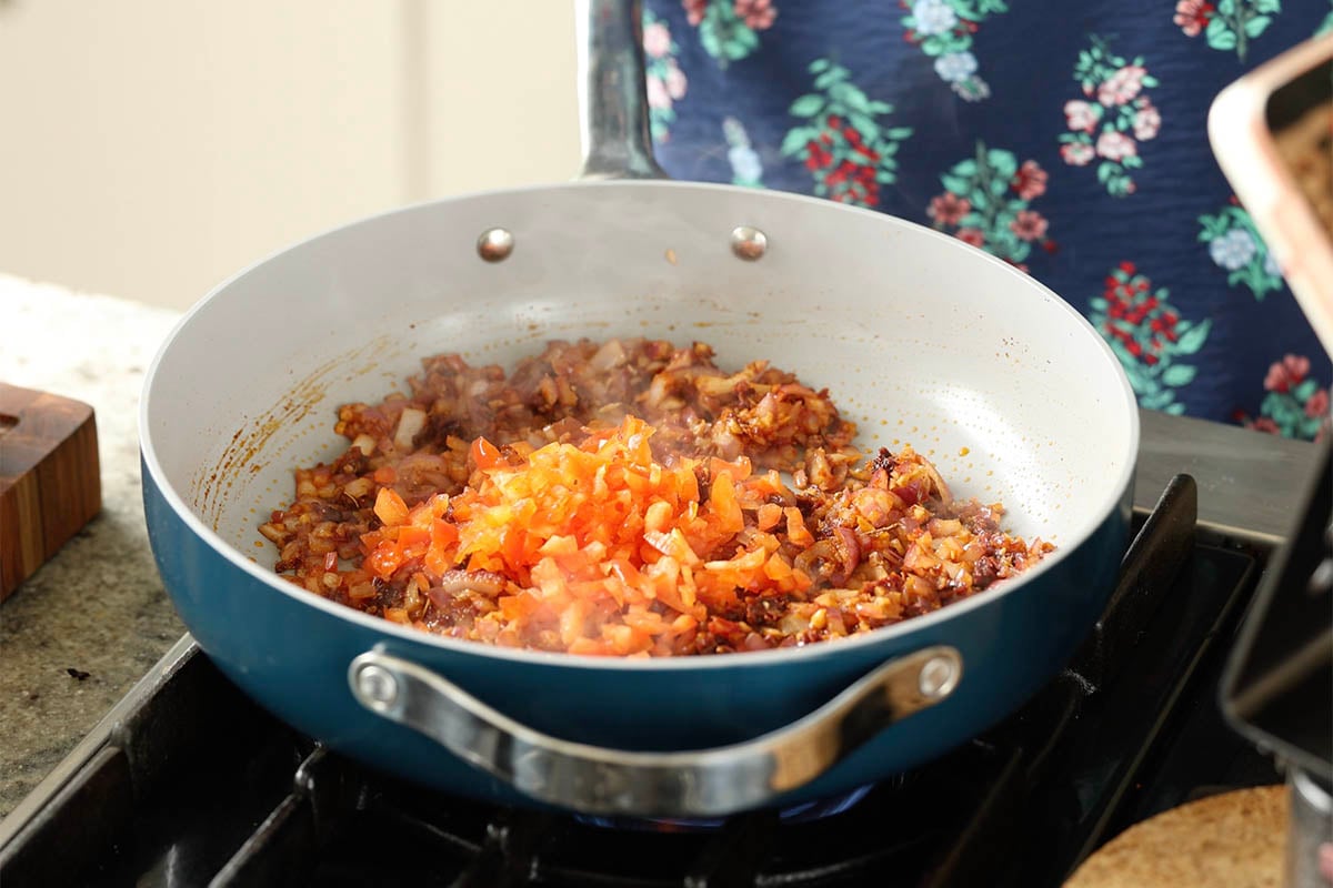 adding tomatoes to the pan