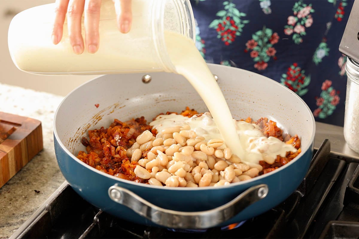 adding white beans and cream to the pan